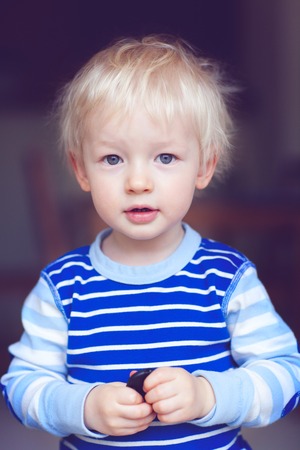 portrait of adorable blond toddler with blue eyes looking straightの写真素材