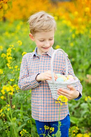 smiling positive kid holding basket full of easter eggs after egg hunt enjoying blooming time at...