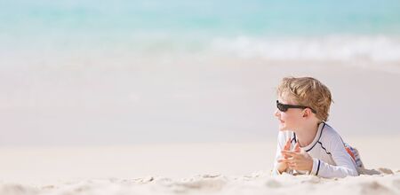 panorama of little smiling caucasian boy in sunglasses enjoying summer vacation at perfect caribbean beach, copyspace on the leftの写真素材