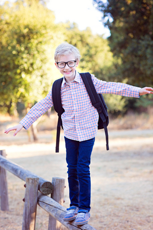 cute school boy student in glasses and with backpack enjoying time outdoor, back to school conceptの写真素材