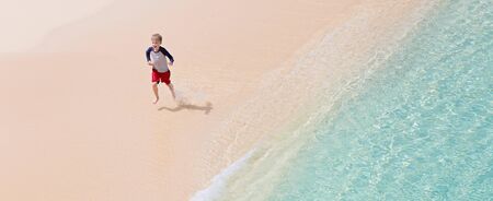 panorama of cheerful little boy running at perfect caribbean beach at anguilla island, copyspace on the rightの写真素材