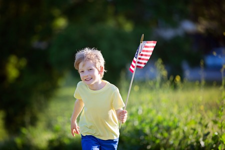 happy smiling little boy running with american flag, celebrating 4th of julyの写真素材
