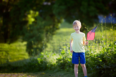 happy smiling little boy standing with american flag, celebrating 4th of julyの写真素材