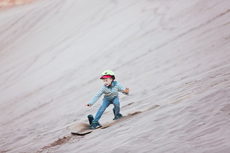 brave little boy sandboarding in valle de la muerte in atacama desert, chile, active healthy lifestyle conceptの写真素材