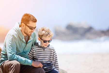 young father and his smiling son enjoying time together at the beach, father's day concept, copy space on the rightの写真素材
