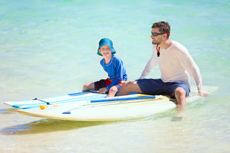 happy family of two, father and his son, enjoying active vacation at fiji island resting after stand up paddleboardingの写真素材