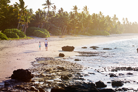 beautiful view of tropical island beach at sunset and father with his son walking togetherの写真素材