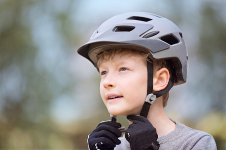 little caucasian boy putting bike helmet on, safety conceptの写真素材