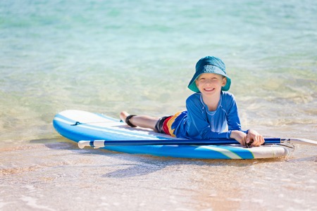 cheerful little boy enjoying stand up paddleboarding alone, active vacation conceptの写真素材