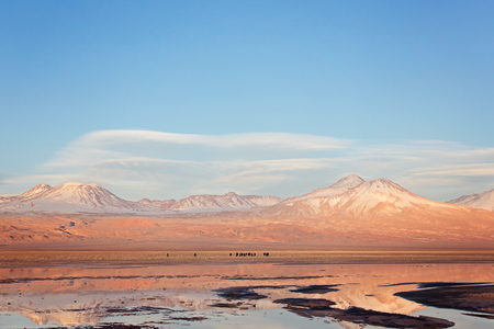 landscape view of salt lagoons, people silhouettes and andes mountains in los flamencos national reserve in atacama desert, chile at sunsetの写真素材