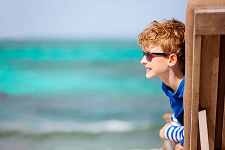 portrait of handsome little boy in sunglasses enjoying tropical vacation and turquoise lagoon at st vincent and the grenadines, beautiful caribbean destination, fun family vacation concept, copy space on leftの写真素材