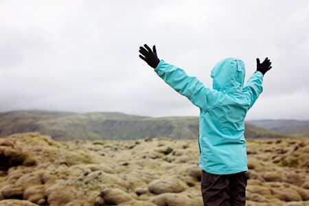 back view of little boy with hands up in the air enjoying mossy fields in iceland, active vacation conceptの写真素材
