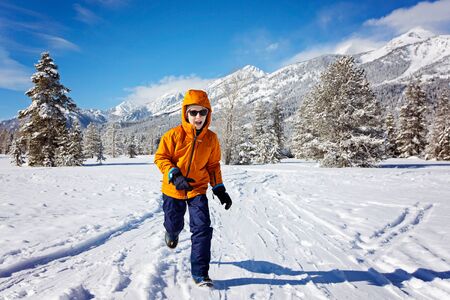 active little boy running and enjoying snowy winter at beautiful sunny day at grand teton national parl, wyoming, usaの写真素材