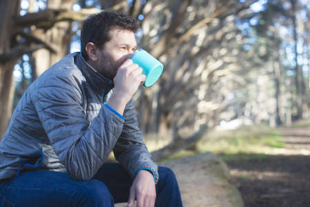positive man outdoor enjoying his drink out of reusable cup, environmentally friendly option, zero waste conceptの写真素材