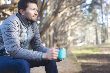 positive man outdoor enjoying his drink out of reusable cup, environmentally friendly option, zero...