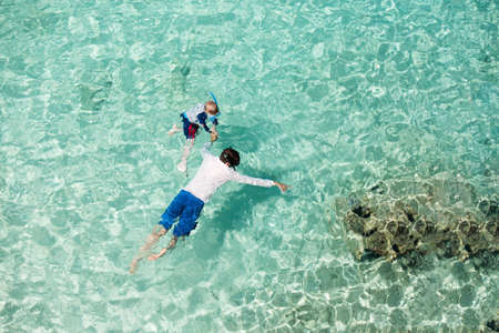above aerial view of family of two, father and son, snorkeling together in beautiful caribbean turquoise waters enjoying active family vacation, aqua menthe - 2020 year color trendの写真素材