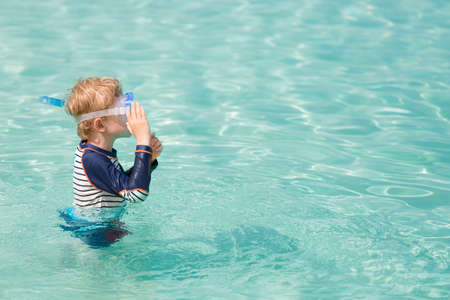 little boy ready for snorkeling in beautiful caribbean turquoise waters enjoying active family vacation, copy space on right, aqua menthe - 2020 year color trendの写真素材