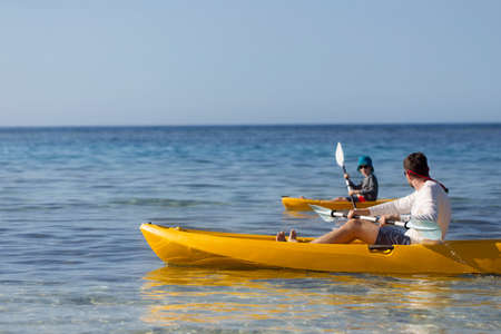 side view of family of two, father and son, enjoying kayaking together, active family summer vacation concept, copy space on leftの写真素材