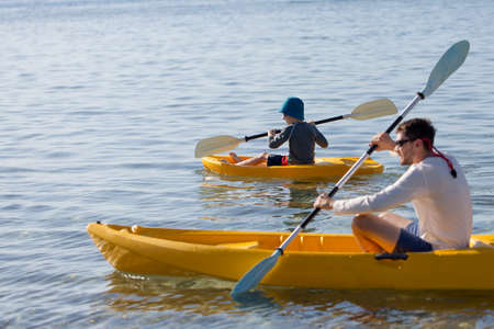 side view of family of two, father and son, enjoying kayaking together, active family summer vacation concept, copy space on leftの写真素材
