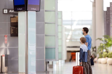 family of two, father and son, in face masks standing with the luggage in the airportの写真素材