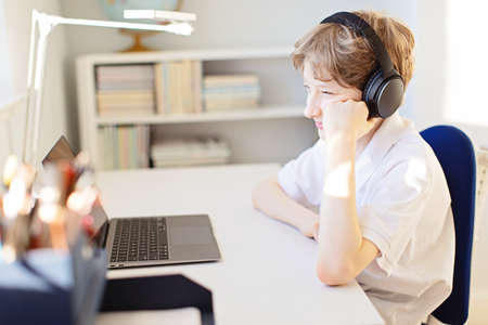 positive smiling boy online learning at home during  pandemic using laptop and headphonesの写真素材