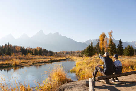 family of two, father and son, hiking and enjoying the gorgeous views in grand teton national parl, wyoming, during fall, active family vacation conceptの写真素材