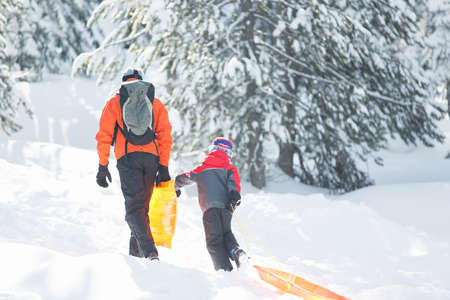 excited little boy and his father ready for sledding, enjoying winter fun activities togetherの写真素材