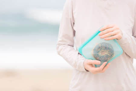 woman with no face visible holding silicone reusable snack bag with food inside, zero waste concept, copy space on leftの写真素材
