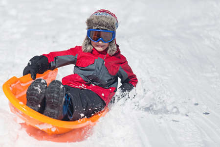 happy and positive little boy enjoying sledding and cold weather outdoor, winter fun activity conceptの写真素材