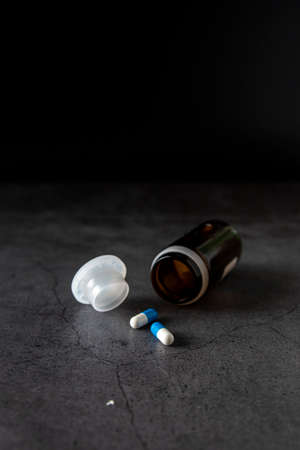 Painkiller pills out of the container on a dark backgroundの写真素材
