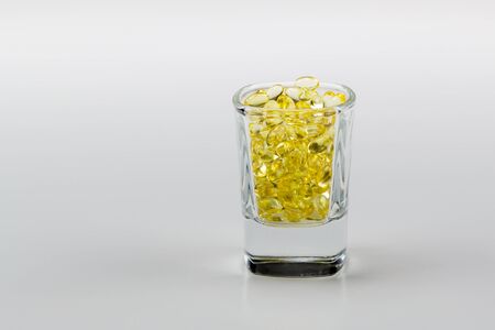 Vitamin E Pills Capsules White Background Isolated in shot glass tight view close cropの写真素材