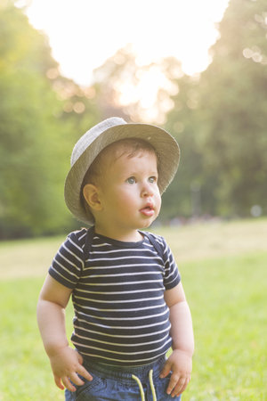 Portrait of a baby boy in a hat on the grass in the park