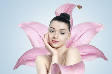 Beautiful brunette woman with pink flower - skin care conceptの写真素材