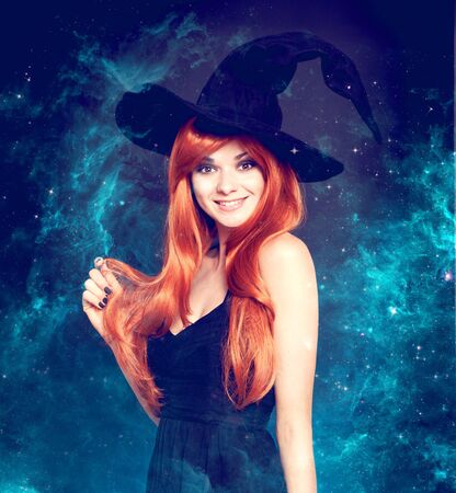 Beautiful young woman as halloween witch with scroll-magical portraitの写真素材