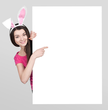 Beautiful young woman as easter bunny with white boardの写真素材