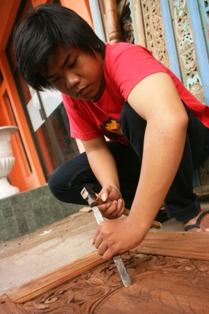 YOGYAKARTA- OCTOBER 28  Traditional craftsman carving wood with floral motifs on October 31, 2008 in Yogyakartaのeditorial素材