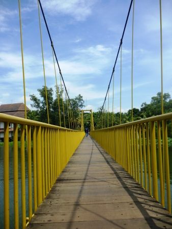 A wooden suspension footbridge spans the width of a river Mekarsari fruit garden, Bogor, Indonesiaの写真素材