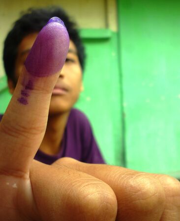 young boy dips of one of her fingers into the ink as a sign that she has voted in in Indonesia presidential election, 9 July 2014のeditorial素材