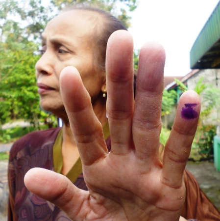 old mother dips of one of her fingers into the ink as a sign that she has voted in in Indonesia presidential election, 9 July 2014のeditorial素材