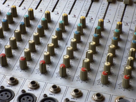 Side closeup on a sliders of a mixing console. It is used for audio signals modifications to achieve...