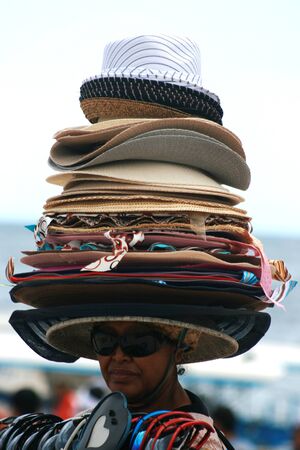 TANJUNG BENOA, INDONESIAN REPUBLIC - DECEMBER 21: Unidentified woman trying to sell colorful hats under the tanjung benoa sun on December 21, 2014 in Indonesian Republicのeditorial素材