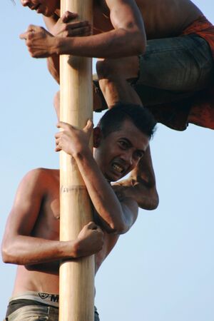 Male indonesian bamboo pole climbing wet slippery for prizes dalam acara memperingati hari kemerdekaan indonesia setiap 17 agustusのeditorial素材