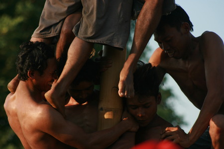 Male Indonesian bamboo pole climbing wet slippery for prizes in a ceremony commemorating the Indonesian Independence Day every August 17のeditorial素材