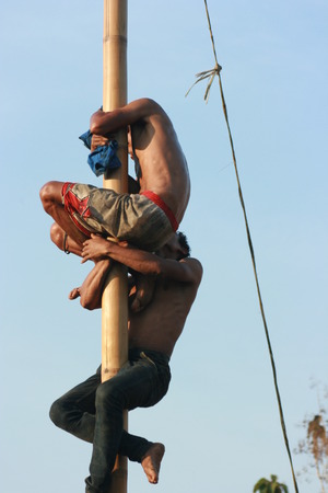 Male Indonesian bamboo pole climbing wet slippery for prizes in a ceremony commemorating the Indonesian Independence Day every August 17のeditorial素材