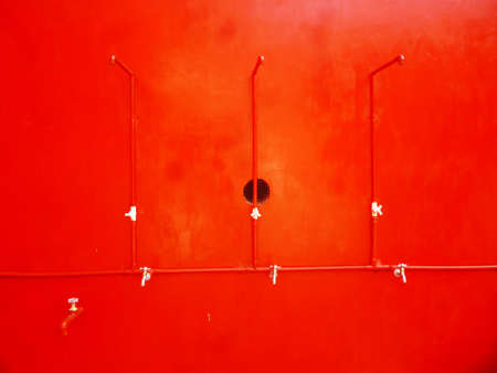 Water flows from a tap on a red backgroundの写真素材