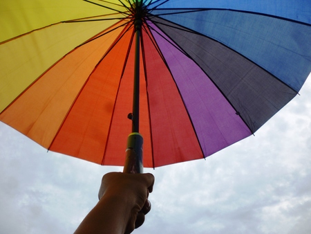 Opened colourful umbrella under blue sky with handy