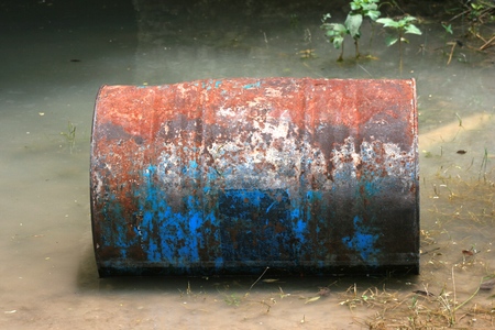 Rusty metal barrel floating in riverの写真素材
