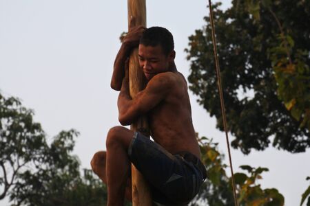 man expression in Indonesian bamboo pole climbing wet slippery for prizes in a ceremony commemorating the Indonesian Independence Day every Augustのeditorial素材