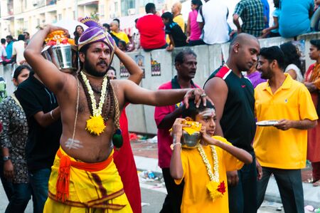 20 January 2011, Kuala Lumpur, Malaysia: A son leads his father as they carry offerings of sweet milk at the annual Thaipusam festival.のeditorial素材