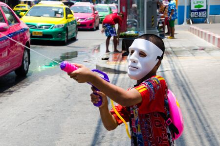 Bangkok, Thailand, 14 April 2015. A masked Thai child squirting passing motorists with a water pistol.のeditorial素材